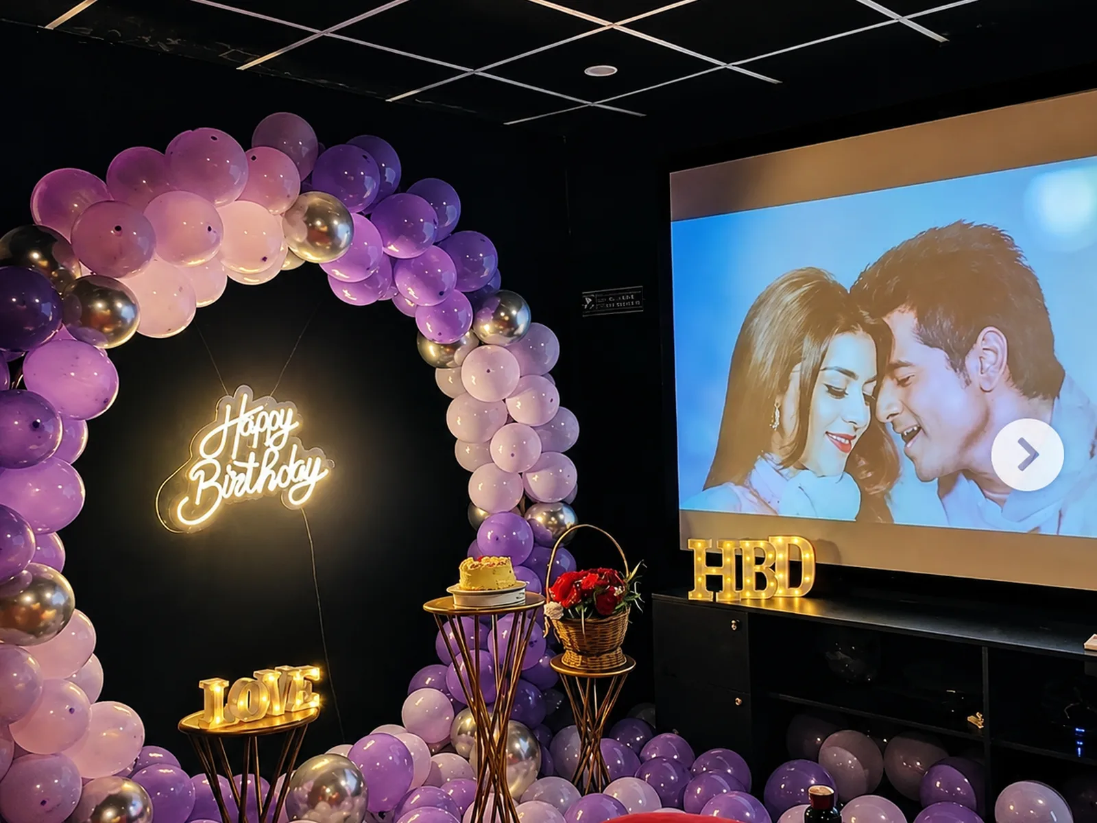 A film playing on the projection screen in a ShowTime Mini room, beside a balloon ring and a lit sign